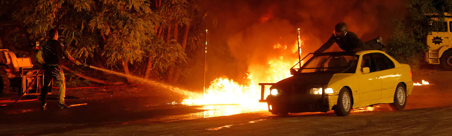 Passage dans le feu, d'une voiture à laquelle s'accroche un cascadeur (sur le toit).