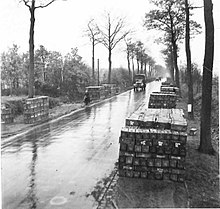 Ammunition piled up alongside a road from whence it is collected Ammunition piled up alongside the road from where they are collected by Units.jpg