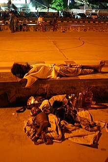 Homeless child pictured sleeping rough with what appears to be their father. Homeless child India 20009.jpg