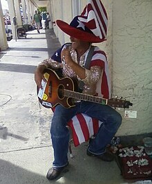 Street performer on Duval Street, Key West, Florida with displayed permit on guitar Key West Florida - Street guitarist with flamboyant Uncle Sam outfit, October 2008.jpg
