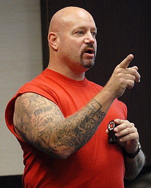 Photograph of Lawton wearing a red shirt and pointing