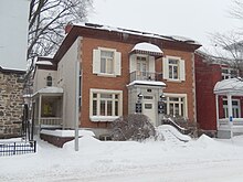 A photo of a two-storey residential building with a side porch
