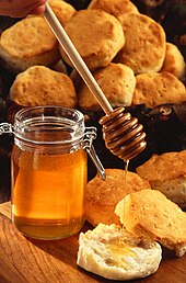 A jar of honey with a dipper and a biscuit Runny hunny.jpg