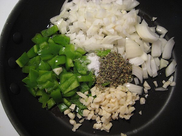 Sofrito being prepared from bell pepper, onion, garlic, and herbs