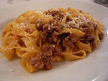 Photographie d'un plat de pates avec des bouts de viande.