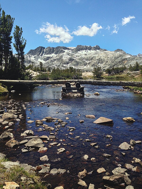 A log bridge on the John Muir trail crossing part of Thousand Island Lake. Mount Davis is visible in the background.