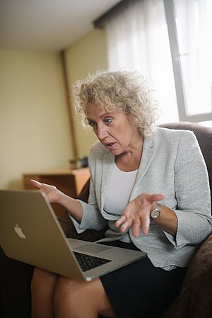 Woman looking confused while sitting in an armchair with a laptop in her lap. (51535516007).jpg