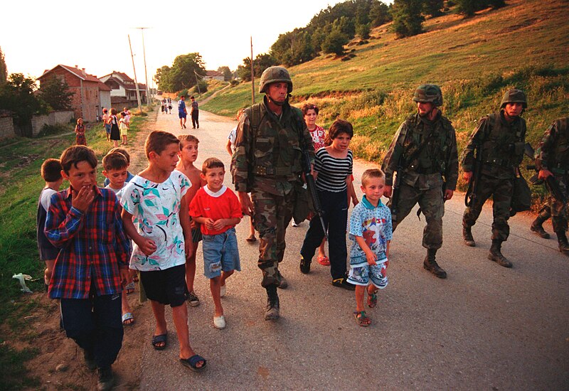 File:990628-M-5696S-025 - U.S. Marines march with local children down street of Zegra, Kosovo.jpg