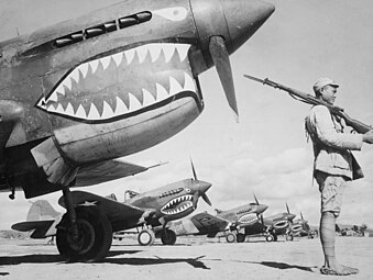 Soldado chinês guardando uma linha de aviões de combate americanos P-40, pintados com o emblema de tubarão dos Flying Tigers