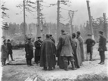 Photographie de travailleurs parlant avec des officiers de l'armée russe dans une forêt au sol enneigé lors de la construction d'un chemin de fer.