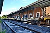 A train of empty flatcars passes the new Chascomús train station in 2014