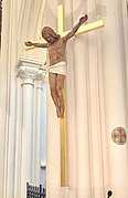 Superbe Croix en bois doré avec Jésus Christ crucifié, seulement vêtu du périzonium (ou Saint Pagne) constitué avec l'écharpe de l'auteur de cette œuvre, le sculpteur Alain Savariau. Le bois utilisé provient d'une charpente du Mont-Saint-Michel déposée et remplacée au cours de travaux récents.