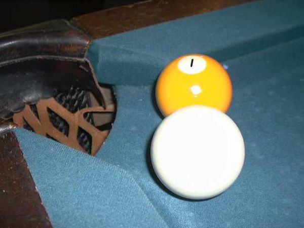 A cue ball and the 1 ball close to a WPA-style pocket. (The balls are the same size; the cue ball looks large due to foreshortening.)