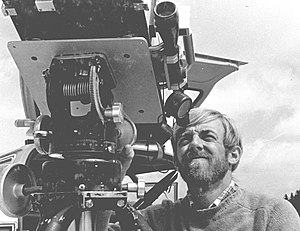 Black and white photograph; a man squints into the telescopic eyepiece of a large mechanical device.