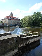 Das Emswehr in Rheine; im Hintergrund die barocke Mühle, Nachfolgerin der erstmals im 14. Jahrhundert erwähnten Mühle. Heute arbeitet die Mühle als Wasserkraftwerk zur Stromerzeugung