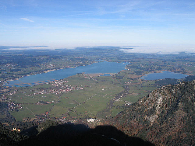 A northward view of Neuschwanstein Castle from Mount Säuling (2,047 m or 6,716 ft) on the border between Bavaria and Tyrol: Schwangau between large Fo