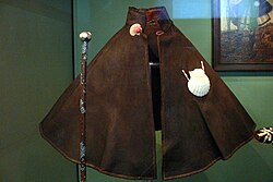 1571年のサンティアゴ巡礼者の服。 巡礼者バッジ（英語版）を付けたマント、 巡礼者の杖（英語版）(武器となる仕込み杖など)、 巡礼者の帽子（英語版） カバン