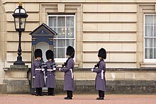 A sentry at Buckingham Palace being relieved during the changing of the guard. Guards at Buckingham Palace (32629261244).jpg