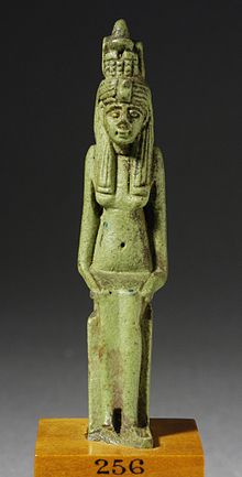 A small green faience statue of a woman seated with a fish over her head.