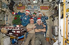 ISS crew with festive Christmas hats aboard the Zvezda service module of ISS in 2009. ISS christmas 2009.jpg