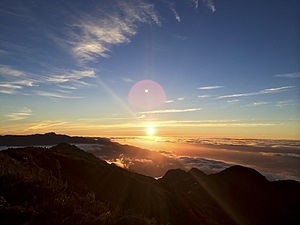 Sunrise seen from the top of Pedra da Mina. The Itatiaia Massif can be seen to the left in the background. Its highest summit, visible in the picture, is Pico das Agulhas Negras, which until 2000 was thought to be the highest point of the Mantiqueira Mountains, but was then found to be actually about 7 metres (23 ft) lower than Pedra da Mina. The two peaks are approximately 20 km (12 mi) apart as the crow flies.