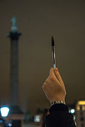 A demonstrator in London holds up a pen, with Nelson's Column in the background