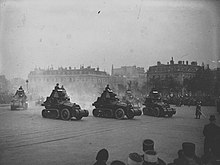 Photographie de cinq automitrailleuses Schneider-Kégresse défilant devant des immeubles parisiens