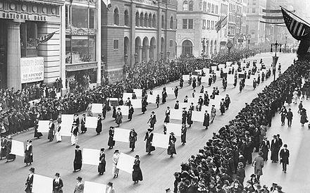 Défilé de militants en faveur du droit de vote pour les femmes à New York en 1917 ; les personnes montrent des panneaux portant les signatures de plus d'un million de femmes[1].