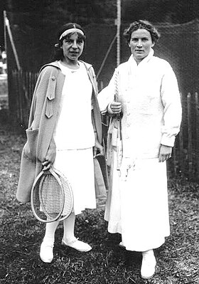 Lenglen and Ryan posing with rackets off the court in their tennis attire