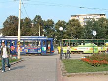 Zdjęcie. Tramwaje typu GT6 (z lewej) i 105Na (z prawej) mijają się na placu Grunwaldzkim. Za nimi widoczne zadrzewienie placu i powojenny blok mieszkalny.
