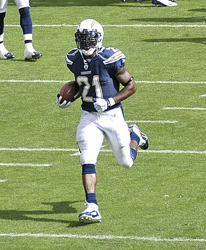 LaDainian Tomlinson carrying a football in his San Diego Chargers uniform and helmnet.