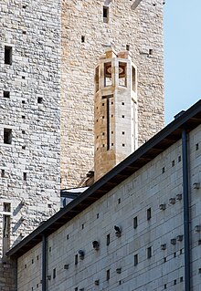 Zdjęcie wieżyczki na dachu kościoła, zrobione od dołu poziomu ziemi. Wieżyczka jest ośmioboczna i zrobiona z piaskowca. W tle fragment ściany dużej wieży (także z piaskowca). Wieżyczka u samej góry posiada kilka prostokątnych okien.