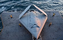 An X-47B with folded wings on the aircraft elevator of George H.W. Bush on 14 May 2013