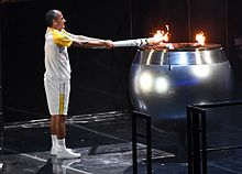 Marathon runner Vanderlei de Lima lighting the Olympic flame Vanderlei Cordeiro de Lima lights cauldron (28771915476).jpg