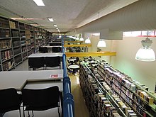 Imagem interna da Biblioteca Acácio José Santa Rosa, mostrando estantes do acervo, mesas e cadeiras de estudos