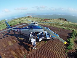 Navy contractors from PMRF arrive at Paniau Ridge on Niʻihau in an Agusta A109 helicopter. The seabird sanctuary island of Lehua can be seen in the background.