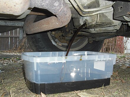 Oil being drained from a car into a drip pan