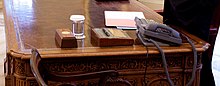 a close-up view of the resolute desk showing the Presidential call button and the HMS Gannet pen holder.