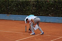 A chair umpire checks the mark of the ball on clay. Tennis Check sign.jpg