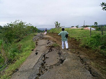 Residentes en la zona de Cinchona intentan escapar de la zona devastada por un camino destruido.
