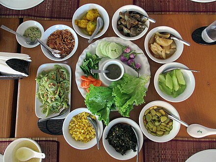 A plate of ngapi yay gyo is surrounded by an assortment of traditional Burmese curries and dishes.