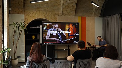 Учасники й учасниці локальної вікізустрічі у Києві до міжнародної Вікіманії дивляться віртуальну програму конференції