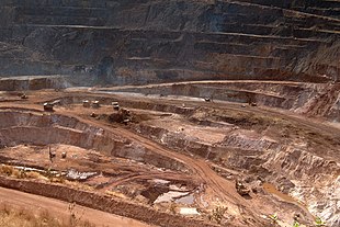 Miniera d'oro a cielo aperto attraversata da molti macchinari edili.