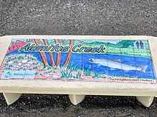 A painting on tiles on a bench symbolizing Los Alamitos Creek's marine life, footbridges & public recreation