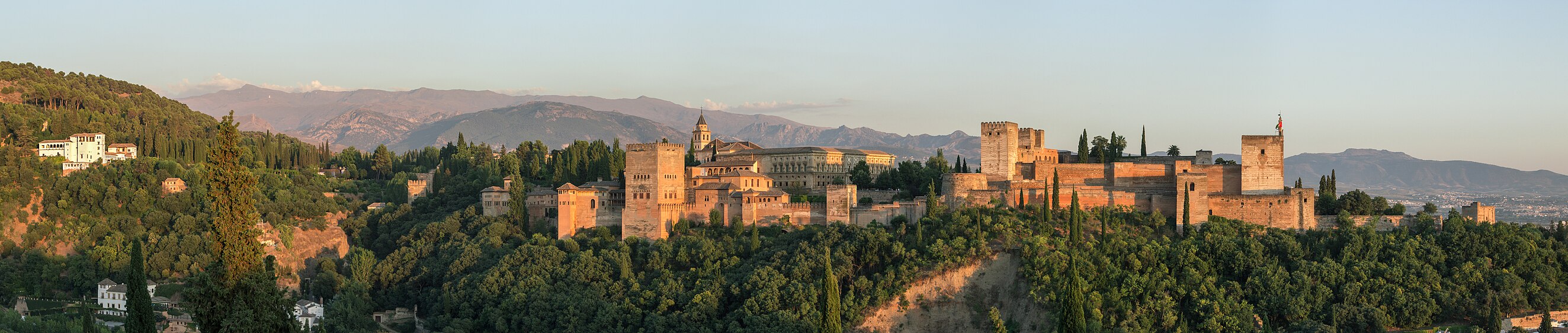 An evening panorama of the Alhambra as seen from Mirador de San Nicolás with the Sierra Nevada mountain range in the background. From left to right: Generalife, Pico del Veleta (mountain), Palacios Nazaríes, Palace of Charles V, Alcazaba.]]