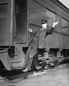 A U.S. railroad worker serving as a brakeman on a passenger train circa 1919