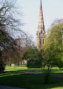 Виден высокий шпиль церкви через парк 