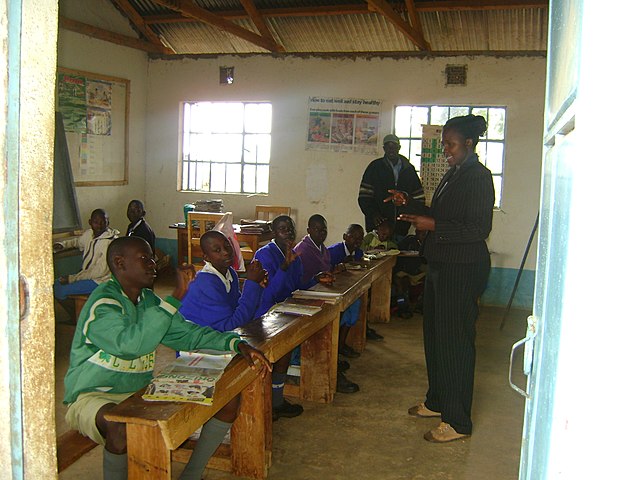 Smiling teacher standing in front of eight older boys in Africa