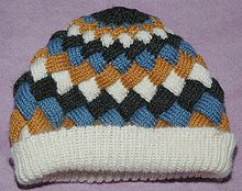 Illustration of entrelac. The blue and white wales are parallel to each other, but both are perpendicular to the black and gold wales, resembling basket weaving. Entrelac-hat.jpg