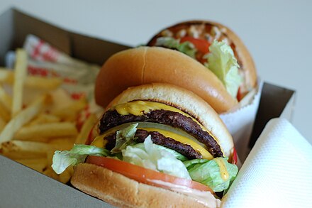 An In-N-Out "Double-Double" cheeseburger with French fries in a cardboard box for consumption in a car